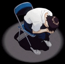 a man is sitting on a blue folding chair with his head down .