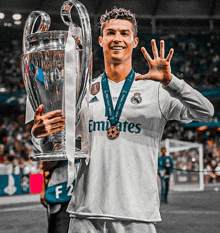 a soccer player holding a trophy with a medal around his neck that says emirates