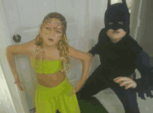 a boy in a batman costume stands next to a girl in a belly dancer outfit