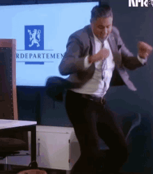 a man in a suit and tie is dancing in front of a screen that says rddepartement