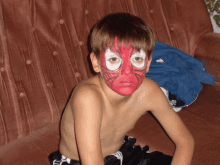 a young boy with his face painted like a spider man