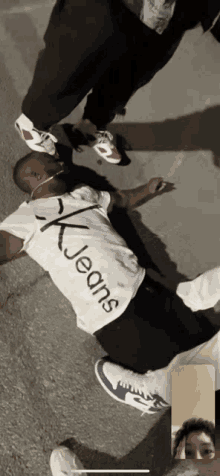 a man wearing a calvin klein jeans shirt laying on the ground