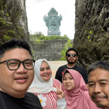 a group of people are posing for a picture in front of a large statue