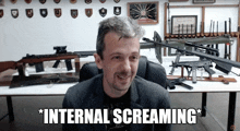 a man is sitting in front of a table full of guns and the words internal screaming