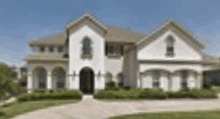 a large white house with a brown roof and a driveway .