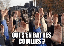 a crowd of people raising their hands in the air with the words `` qui s ' en bat les couilles ? ''