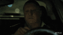 a man in a car with a netflix logo on the bottom of the screen