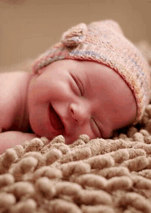 a newborn baby wearing a knitted hat is sleeping on a blanket .