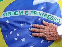 a person 's hand rests on a brazilian flag that says ordem e progresso