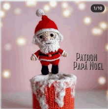 a crocheted santa claus figurine is standing on top of a christmas gift box .