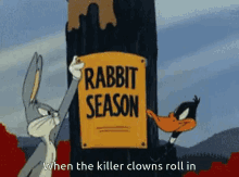 bugs bunny and daffy duck holding up a sign that says rabbit season