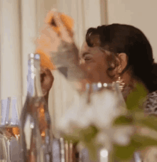 a woman is pouring a drink into a glass at a party .