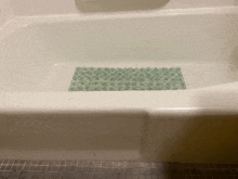 a bathtub with a green mat on the floor .