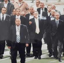 a group of men in suits and ties are walking down the street