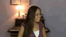 a woman is sitting in front of a piano with a lamp and a calendar on the wall behind her