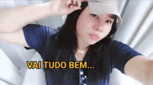 a woman wearing a hat takes a selfie with the words vai tudo bem