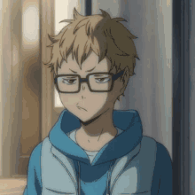 a boy wearing glasses and a blue hoodie is making an angry face