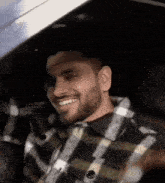 a man is sitting in the driver 's seat of a car and smiling .