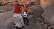 a man wearing a traffic cone on his head is holding a drill