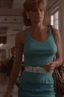 a woman in a blue tank top and blue skirt is walking