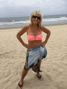 a woman in a pink bikini stands on a beach