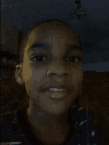 a young boy taking a selfie in a dark room with a chandelier in the background