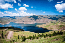 a lake with mountains in the background and a dirt road going through it