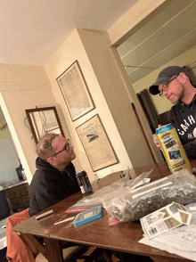 two men are sitting at a table with a can that says ' the new york times '