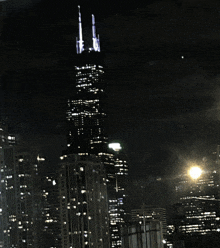 a city skyline at night with a tall building in the foreground