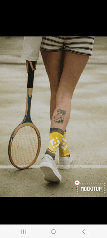 a woman with a tattoo on her leg holds a tennis racket