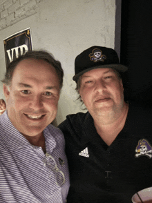 two men posing for a picture with one wearing a black adidas shirt