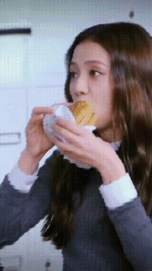 a woman is eating a sandwich with a napkin around her mouth