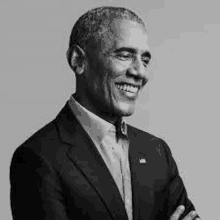 barack obama is smiling in a black and white photo while wearing a suit and tie .