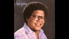 a man wearing glasses and a purple shirt is smiling on the cover of his album .