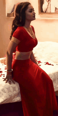 a woman in a red dress sitting on a bed