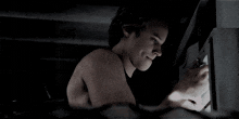 a shirtless man is looking at a cockroach in a dark room