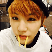 a young boy with orange hair is eating french fries