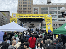 a crowd of people are gathered under a nyc cannabis parade sign