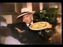 a man in a hat holds a plate of food