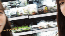 two women standing next to each other in front of a shelf in a store with foreign writing on it