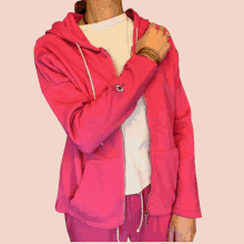 a woman wearing a pink hoodie with an eye embroidered on the sleeve