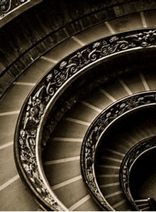 a black and white photo of a spiral staircase with a fancy railing