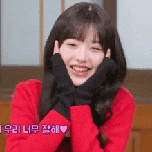 the girl is wearing a red sweater and black gloves and smiling .