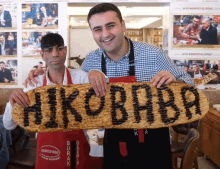 two men holding up a sign that says ' hukobaba ' on it