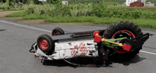 a white vehicle with red and green wheels is upside down