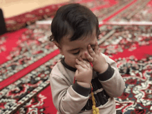 a little boy wearing a shirt that says new york covering his face with his hands