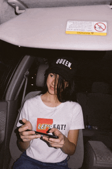 a woman wearing a black hat that says queen