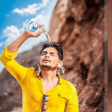 a man in a yellow shirt pours water from a bottle