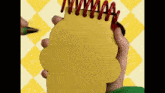 a person is holding a yellow notepad with a red pen