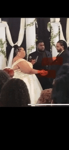 a bride and groom are standing in front of a crowd at a wedding ceremony .